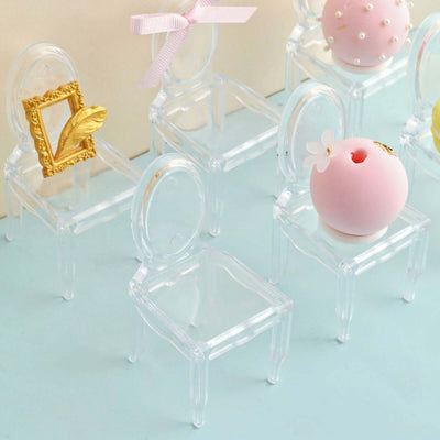 Miniature transparent chairs with decorative items on a pastel surface.