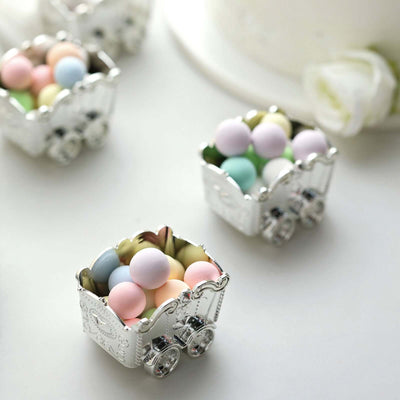 Silver decorative carts filled with pastel candy pearls on a white background.
