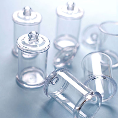 Clear glass jars with lids arranged on a blue surface.