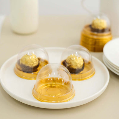 Clear dome dessert cups with golden bases, featuring chocolate treats.