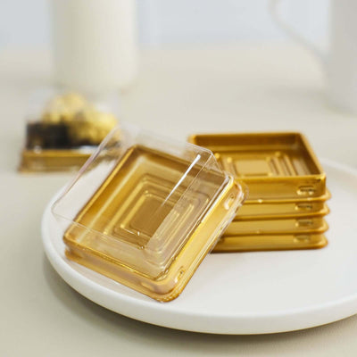 Gold square coasters stacked on a plate with a transparent cover.