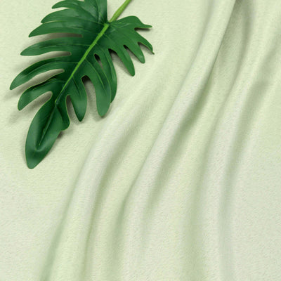 Green fabric with soft drapes and a tropical leaf accent.