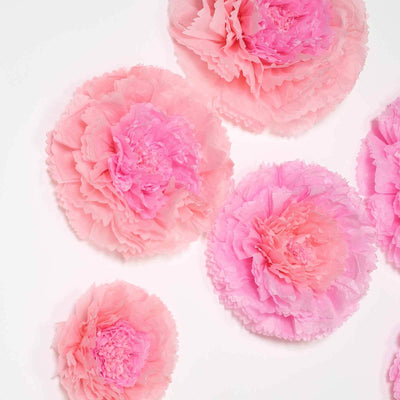 Pink paper flowers in various sizes arranged on a white background.