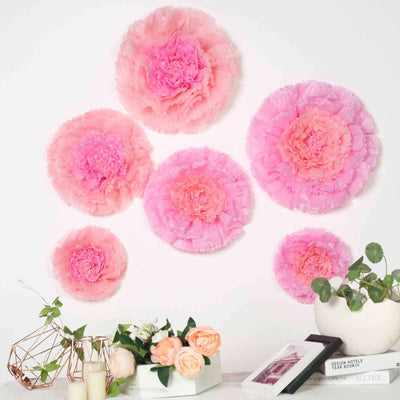 Pink decorative tissue paper flowers on a white wall.