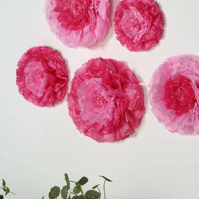 Pink paper flowers in varying sizes arranged on a white background.
