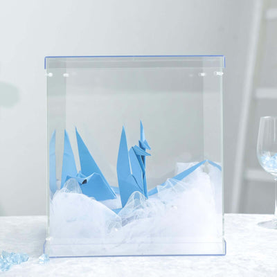 Blue origami display in a glass case with white tulle