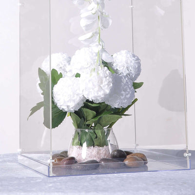 White floral arrangement in a glass vase with pebbles, isolated on a plain background.