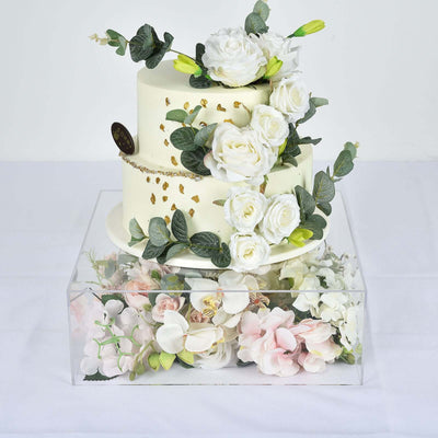 Elegant three-tier cake adorned with white roses and greenery.