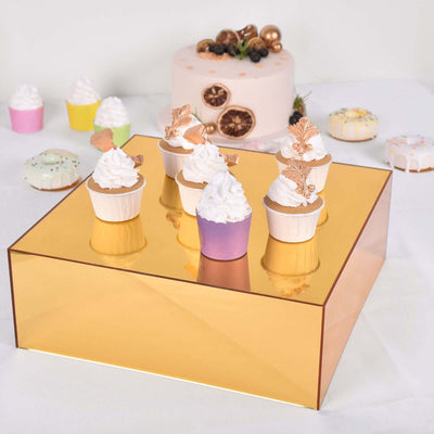 Decorative cupcakes on a gold display stand with a pink cake in the background.