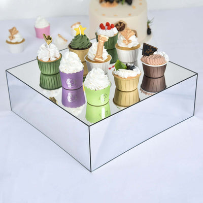 Assorted decorative cupcakes displayed on a mirrored stand.