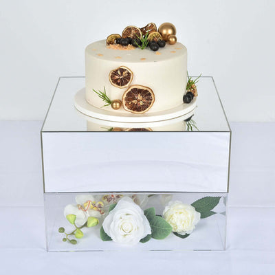 Elegant cake with dried fruits and gold accents on a mirrored stand.