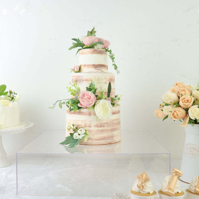 Elegant three-tiered wedding cake decorated with flowers and greenery.
