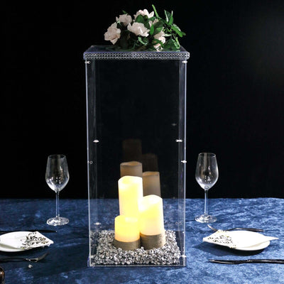 Clear acrylic candle holder with floral decoration and lit candles.