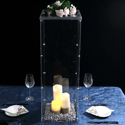 Clear acrylic candle holder with flowers and candles, elegant dining table setting.