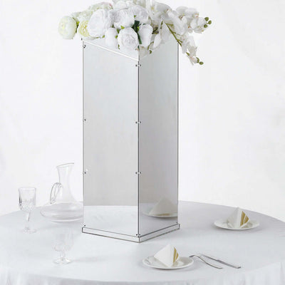 Mirrored floral vase with white roses on a table setting.