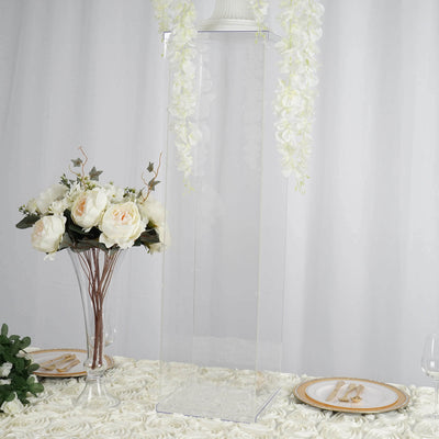 Clear acrylic display pedestal with floral arrangements on a table.