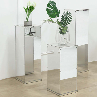 Mirrored display pedestals with vases and greenery in a modern setting.