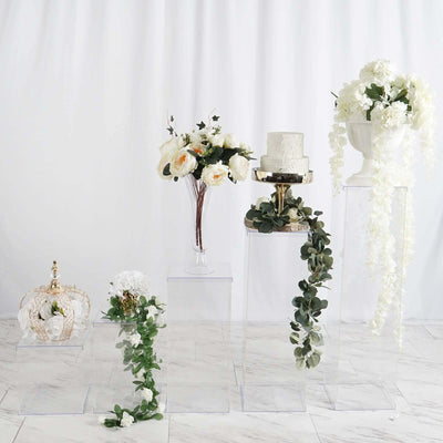 Decorative floral arrangements and cake display on clear pedestals