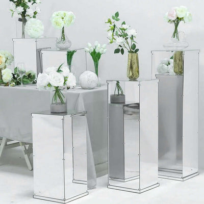 Mirrored flower display pedestals with vases and floral arrangements