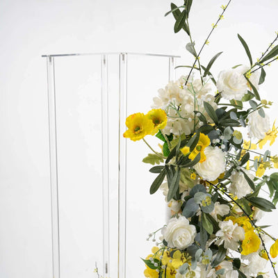Floral arrangement with yellow and white flowers on a clear stand