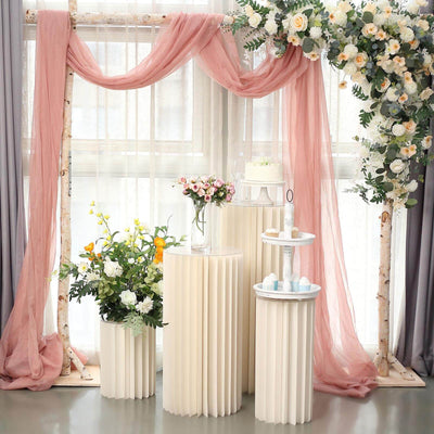 Elegant decorative setup with flowers and cake stands in soft pastel tones.