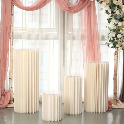 Elegant cream-colored pedestals arranged in a bright, airy space with soft drapery.
