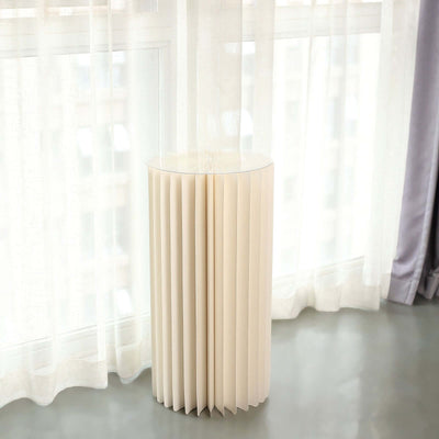 Modern cream-colored pleated side table against a bright window backdrop.