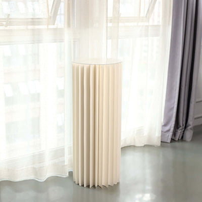 Modern beige pleated side table in a bright, airy room.