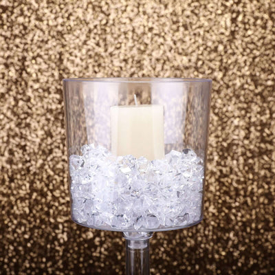 Clear candle holder with decorative crystals and white candle.