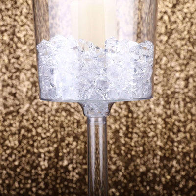 Clear candle holder filled with crystal gems on a glitter background.