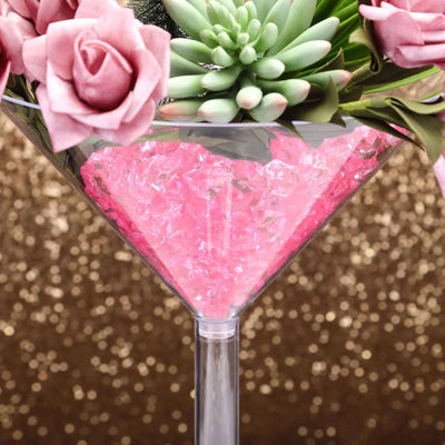 Martini glass filled with pink crystals and decorative flowers.