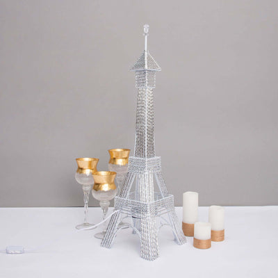 Eiffel Tower lamp with gold and silver candle holders on a neutral background.