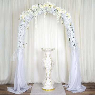 Elegant floral arch with a decorative vase in a serene setting.