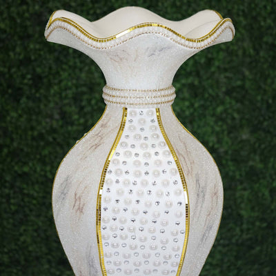 Decorative vase with pearl accents and gold trim on a green background.