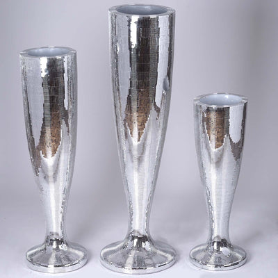 Three sleek, mirrored vases in varying heights on a plain backdrop.