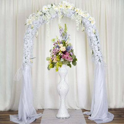 Elegant floral wedding arch with a decorative vase and vibrant flowers.
