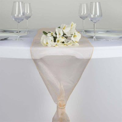 Elegant sheer table runner with floral accent on a dining table setting.