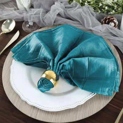 Elegant teal napkin with gold ring on a decorative plate.
