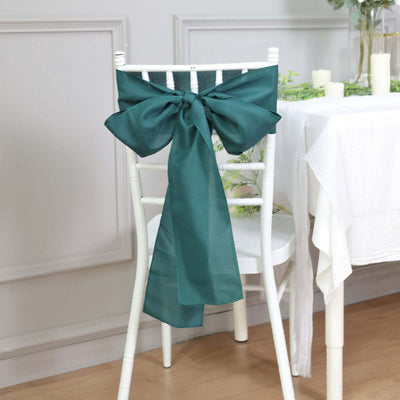 Teal satin chair sash tied in a bow on a white chiavari chair.