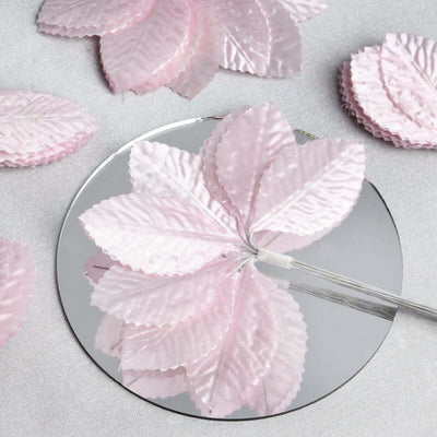 Pink satin leaves arranged on a mirror surface.