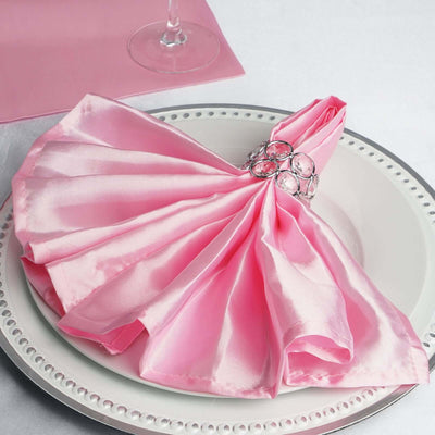 Elegant pink satin napkin with a decorative ring on a plate.
