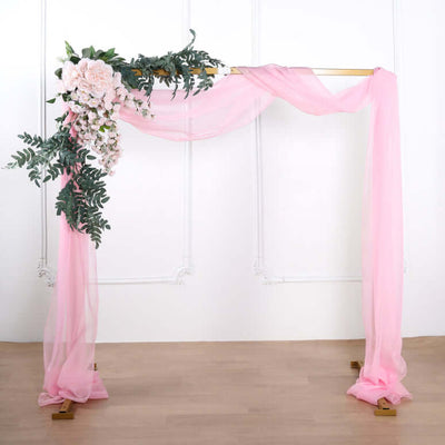 Pink wedding arch with floral decorations and draped fabric.