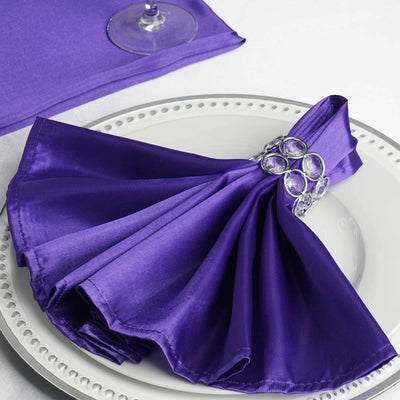 Elegant purple satin napkin with a jeweled ring, beautifully arranged on a plate.