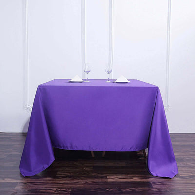 Purple tablecloth draped over a table with two glasses and napkins
