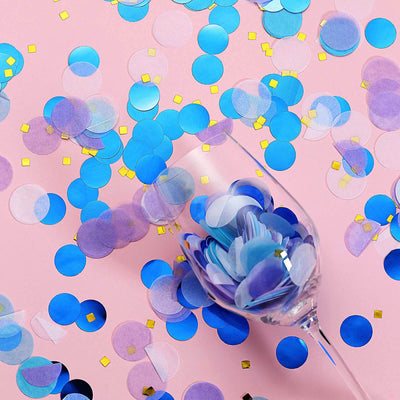 Colorful confetti scattered around a glass on a pink background.