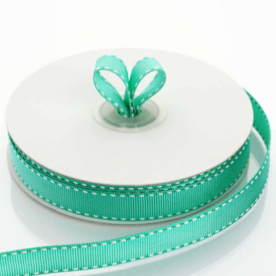 Mint green ribbon on a spool with a heart-shaped loop.