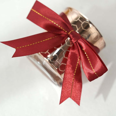 Decorative candle jar with red ribbon and gold accents