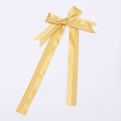 Gold satin ribbon bow with long tails on a white background.