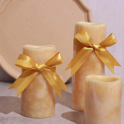 Yellow ribbon candles on a textured surface with a decorative plate in the background.