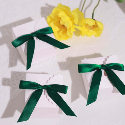 Three white gift boxes with green ribbons and decorative edges.